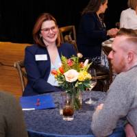 Laura Aikens speaks with a group of alumni at a table